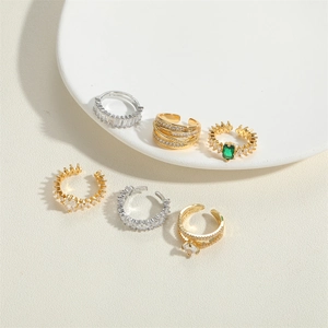 Set of six gold and silver ear cuffs with cubic zirconia stones on ceramic display