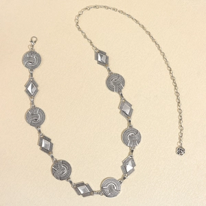Detail of silver chain belt with round textures, diamond motifs, and a rose pendant