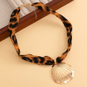 Makroaufnahme von Gold-Muschelanhänger an einem braunen Choker mit Leopardenmuster