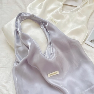 Detail of satin tote bags in pearl white and lavender with delicate silk texture