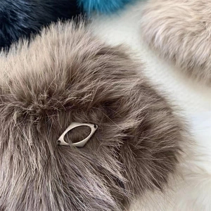 Close-up of fluffy faux fur pompom with a hollow diamond-shaped silver metal ornament