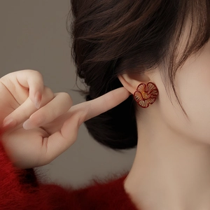 Detail of elegant red floral earring with gold plating on model wearing red sweater
