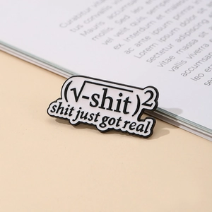 Creative enamel pin with math formula text displayed on an open book background