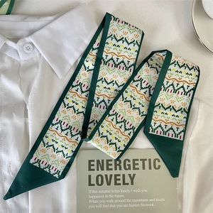 Detail of green silk scarf with geometric pattern on a white shirt with decorative card
