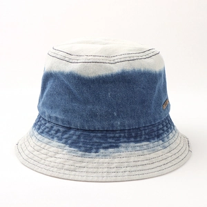 Détail d'un chapeau bob en denim dégradé avec bords effilochés et logo métal