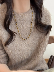 Détail du collier de perles œil de tigre porté sur un pull en mohair marron doux