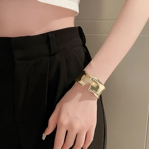 Detail of wide gold irregular metal cuff bracelet on model with minimalist style