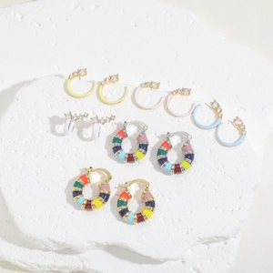 Enamel C-shaped hoop earrings with colorful zircon inlay on white marble display