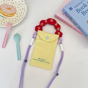 Detail of a bright yellow mini canvas phone bag with red fuzzy handle and embroidery