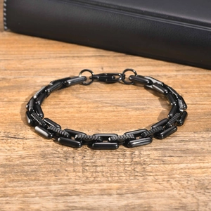 Detail of a black stainless steel geometric link chain bracelet on a leather box