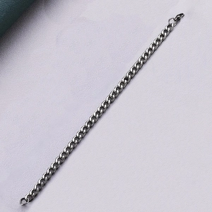 Close-up of a minimalist dark metal Cuban link chain with textured gray background