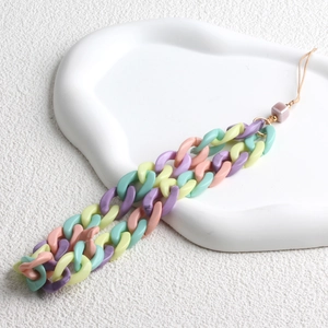 Macro view of macaron colored acrylic phone strap chain on a textured white tray