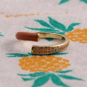 Macro detail of gold ring with brown enamel and pavé-set warm-toned zircons
