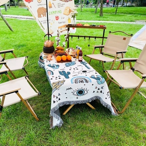 Detailed macro view of bohemian picnic blanket featuring cactus patterns and fringe tassels