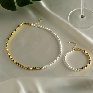 Elegant pearl and gold bead necklace and bracelet set on soft silk fabric background
