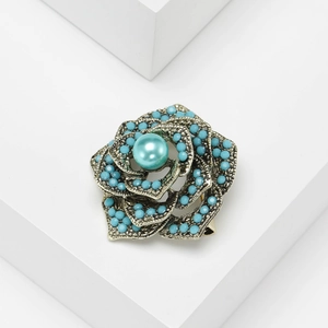 Vintage silver flower brooch with turquoise beads and central pearl on white background