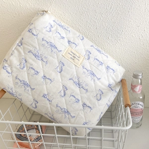 Floral quilted cotton makeup bag with blue puppy print and zipper in white mesh basket