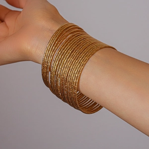 Dettaglio di un set di 20 braccialetti rigidi dorati a strati con finitura scintillante