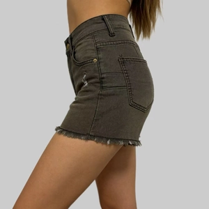 Detail view of distressed dark grey denim shorts with raw hem and ripped texture
