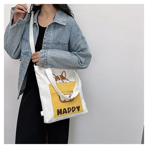 Detail of white canvas crossbody bag featuring a yellow pocket with a Corgi and HAPPY text