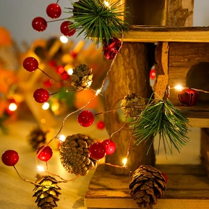 Close-up of LED Christmas garland with pine needles, red berries and natural cones
