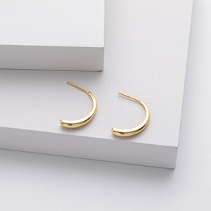 Detailed macro view of S925 sterling silver stamp on polished gold curved earrings
