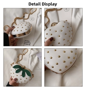 Close-up detail of white strawberry shaped mini bag with gold rivets and chain strap