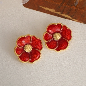 Detailed macro view of vintage red floral stud earrings with gold-toned enamel edges