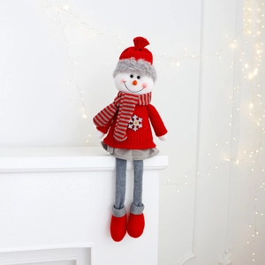 Detail of Christmas snowman doll with striped scarf and red knitted sweater on fireplace