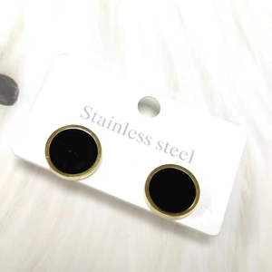 Detailed macro view of black and gold stainless steel round stud earrings on a card