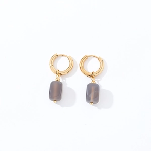 Macro view of geometric gold hoop earrings with translucent grey square stone pendants