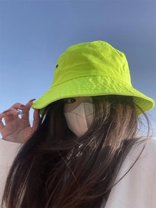 Outdoor shot of a neon green cotton bucket hat with sun protection for street fashion style