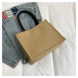 Detail of a large linen tote bag in light brown jute with thick black rope handles