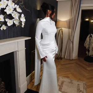 Detail of elegant white long-sleeved evening gown with asymmetrical waist pleats