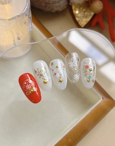 Detail of red and white Christmas nail stickers with gold snowflakes and 3D metal beads