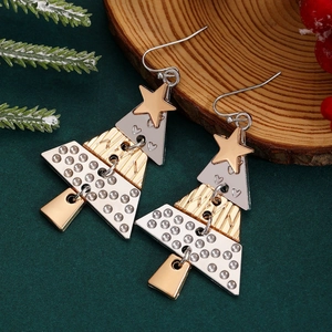 Detailed close-up of Christmas tree earrings with layered metal sheets on pine branch background