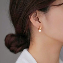 Macro detail of elegant golden hoop earring with a round white pearl on model's ear