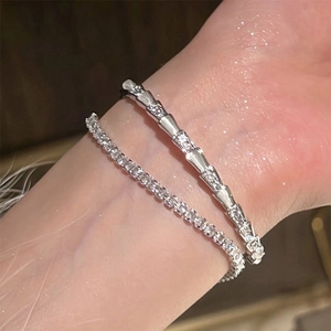 Zilveren slangenarmband en zirkonia tennisketting gedragen aan een vrouwenpols