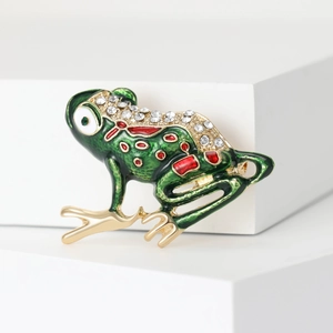 Detailed view of a green enamel frog brooch with crystal rhinestones and gold plating