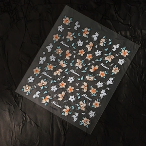 Detail of 5D embossed flower nail stickers with orange petals and crystal accents