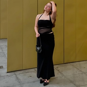 Détail d'un haut licou en mesh noir et d'une jupe longue portés par un mannequin de mode
