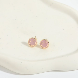 Detailed view of pink enamel smiley face earrings on a cloud-shaped ceramic tray