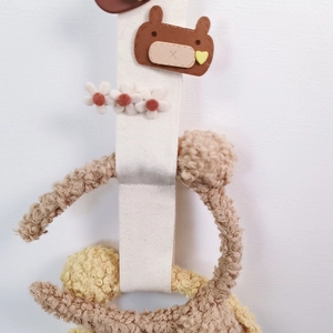 Detail of baby hair clip organizer with brown bear patch and white fabric hanging strap