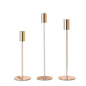 Three Nordic-style gold metal candle holders of varying heights for table decoration