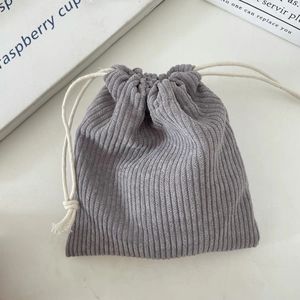 Close-up of light grey corduroy storage bag showing vertical texture and drawstring
