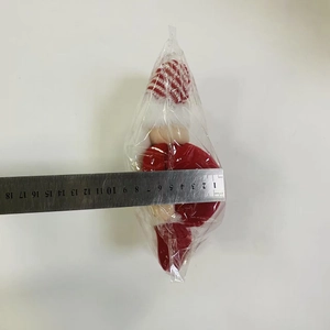 Detailed view of plush Christmas doll in plastic wrap measuring about 10cm with a ruler