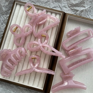 Detail of light pink jelly hair claws in various sizes on a beige textured background