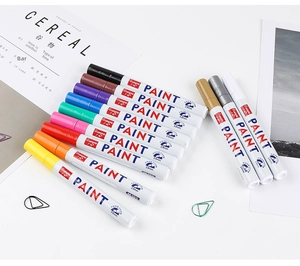 Flat lay of 12-color Guangna M-101 oil paint markers with 2.8mm tips on white desk