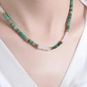 Detail of colorful beads on necklace showing green and white beads with gold spacers