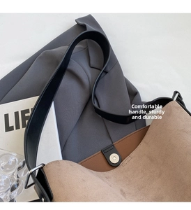 Detail of wide black handle and magnetic closure on large coffee leather bucket bag